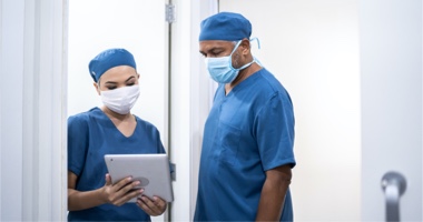 Two physicians with mask looking at tablet - Learning Management HealthStream